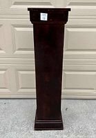 Front view of distressed wooden plant/lamp stand with broad top and decorative base molding.
