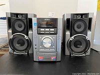 Front view of Sony Mini Hi-Fi stereo system MHC-EC70AM showing main unit and two speakers.