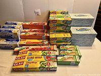 Overview of all items showing multiple boxes of Glad Cling Wrap, Glad Storage Bags, GoodSense Flap-Ties, and tissue boxes with floral design.