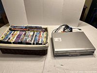 Wide photo showing the Toshiba VHS/DVD player and basket filled with over 40 DVDs and cables.