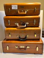 Front stacked view of four vintage Samsonite suitcases showing tan exterior, different colored handles, and gold hardware.