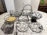 All items arranged on table showing assortment of wrought iron serving and storage pieces with glass bottoms and decorative scrollwork