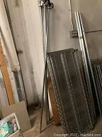 Disassembled metal rails and wire shelves leaning against wall in storage space