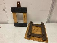 Two small furniture dollies, one wooden with carpet padding and one metal framed with wooden base and wheels.