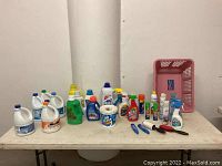 Full view of laundry and cleaning products on table including pink laundry basket and lint rollers.