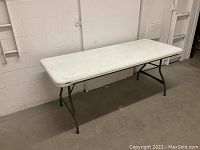 Full view of the Lifetime 6ft plastic banquet table against a white wall, showing the tabletop and metal legs.