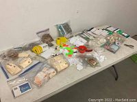 Wide overview of the lot on a table showing grouped supplies including item tags, rubber bands, receipt pads, thumbtacks, tape, and clips