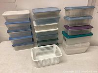 Group photo showing multiple stacks of plastic bins with colored lids and one white plastic basket in front.