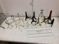 Various wire, plastic, wood, brass plate stands and plexiglass tiered display stand on table.