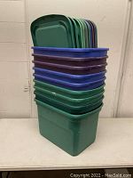 Stack of twelve Sterilite totes in green, purple, and blue, with corresponding lids.