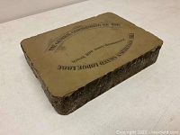 Top and angle view of a rectangular lithography stone showing printed text and designs in black on smooth surface; rough natural stone edges visible