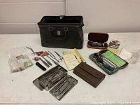 Full display of vintage physician bag with extensive collection of medical tools including scissors, syringes, stethoscope, and cases for instruments, arranged on floor.