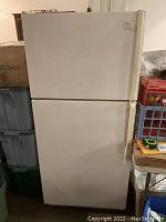 Full front view of the white Whirlpool refrigerator showing top freezer and larger bottom fridge doors in closed position.