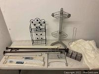 Photo showing black wire rack with star cutouts, multiple metal curtain rods with brackets, white wall-mounted racks, and wire baskets on a table.