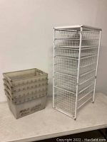 White wire basket storage rack with six wire baskets, placed on a white table with five stacked corrugated plastic delivery bins beside it.