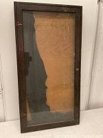 Front view of the wood display cabinet with glass door, showing its rectangular shape and worn dark wood frame.