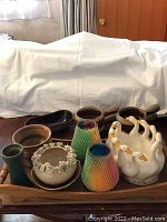 Image showing all ceramic bowls, candle holders, and wooden tray on a wooden surface with white backdrop.