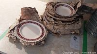 Multiple Johnson Bros Old English china plates wrapped in newspaper.