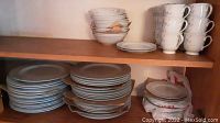 Shelves containing stacks of dinner plates, side plates, cups, and bowls with the Fresh Flowers design by Excel.
