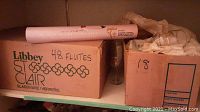 Box labeled 'Libbey St. Clair' containing 48 flutes and another box labeled '18' presumable glassware storage.