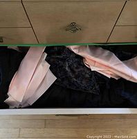 Drawer containing pale pink satin-like fabric and black textured floral fabric.