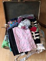 Vintage suitcase opened showing assortment of folded vintage fabrics and a plastic bag of buttons on top
