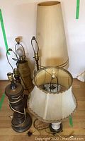 Cluster of six diverse vintage table lamps showing various styles, bases, shades, and wiring.