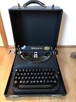 Full view of the open Remington portable typewriter in its black carrying case, showing the keyboard and carriage area.