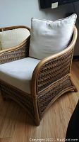 Side angle showing white fabric cushions on bamboo and woven wicker frame chair.