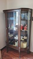 Front view of oak china cabinet containing porcelain figurines (contents not included)