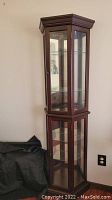 Full view of the wood curio cabinet showing glass doors and shelves, corner placement.