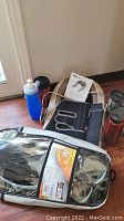 Obus Forme shiatsu and vibration neck massager with heat displayed with its user manual, knee braces, adjustable neoprene back belts, U.S. Divers snorkel mask and fins set in plastic case, and various travel cups including Contigo bottles.