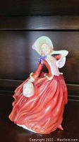 Front view of Royal Doulton Autumn Breezes HN1939 figurine in flowing red dress with basket and bonnet.