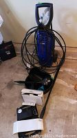 Full view of Simoniz 1500 power washer with hose coiled around, small air compressor and automotive equipment including funnel and oil change tools.