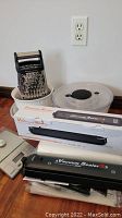 Photo showing vacuum sealer unit, boxed vacuum sealer, salad spinner basket, kitchen scale and KitchenAid grater, all arranged on floor.