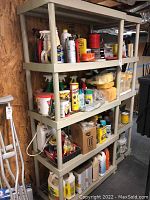 Four shelves stocked with various bottles, cans, and boxes containing bird feeders, sealers, garden products, and car cleaning supplies. Items organized by type across shelves.