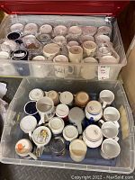 Two plastic bins containing approximately 50 assorted coffee mugs with visible diversity in design and style, tops and bottoms showing variety in shape and color.