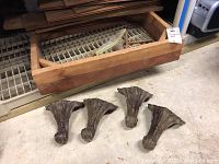 Photo showing four carved claw-shaped wooden legs placed on the floor.