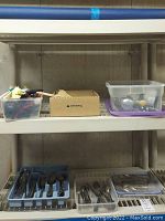 Shelves with plastic containers holding kitchen utensils, flatware organized in trays on bottom shelf