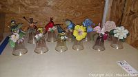 Full set of 10 Franklin Mint figural porcelain bird and flower glass bells, front view on table with wood background