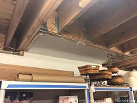 Longaberger baskets with metal stands, box of grass cloth wallpaper, and roll of floor paper visible on shelving in basement.