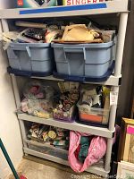Wide view showing three large plastic bins filled with various sewing notions organized on a plastic shelving unit.