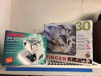 Photo showing boxed Singer Tiny Serger overedging machine model TS380A with product details visible on front of box.