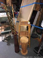 Photo showing wicker shelf, tall brown vase, wooden hexagonal container in a cluttered basement setting.