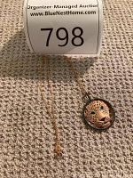 Full view of gold chain and leopard pendant laid flat on carpet with lot tag
