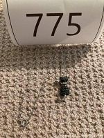 Full view of the white gold chain with cat pendant laid out on carpet.