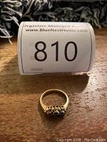 Photo of the 14k gold ring laid flat on wood surface with auction lot tag in background.