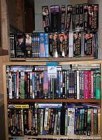 Three shelves filled with assorted DVDs and VHSs of British TV series. Visible titles include Midsomer Murders multiple sets, Foyle's War DVDs and VHS, Downton Abbey box set, Inspector Morse VHS, Rosemary & Thyme, and others.
