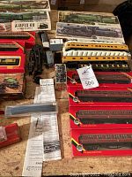Overview of boxed 00 scale passenger train cars, locomotive, and related accessories on a wooden surface.