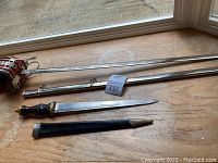 Both decorative blade items and their scabbards laid flat showing full lengths
